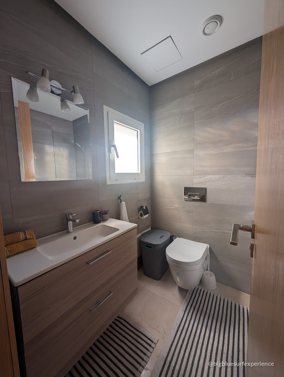En-suite bathroom of the BigBlue Bay Studio with a wooden vanity unit and a frosted window