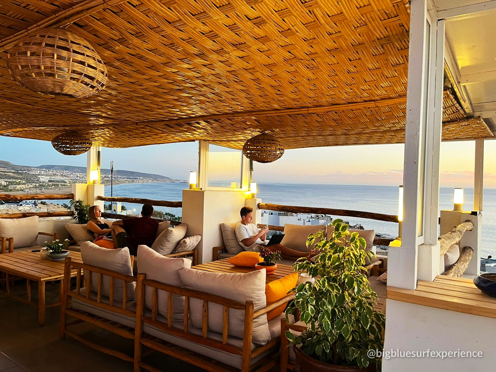The BigBlue rooftop terrace at sunset, guests working and talking above Taghazout bay